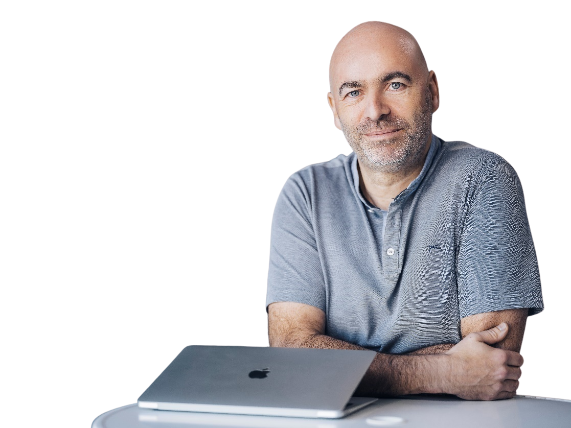 Portraitfoto von Oliver Hohnhold mit Laptop am Tisch.